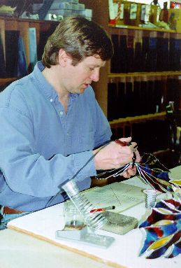 Joseph E. Godek  soldering  stained glass dragons in his home studio